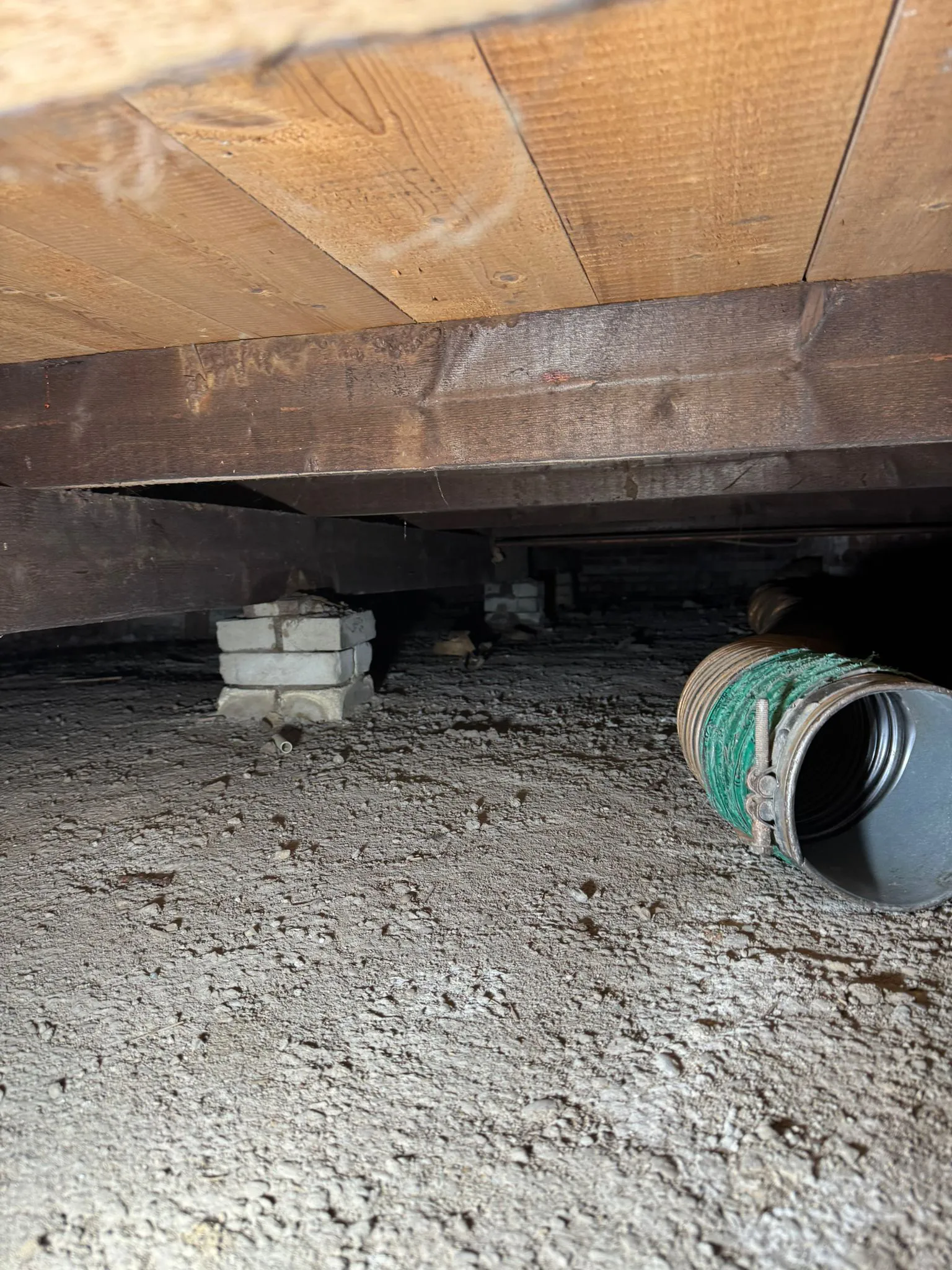 Kruipruimte vóór het aanbrengen van bodemisolatie met zichtbare bodem en houten vloerconstructie.